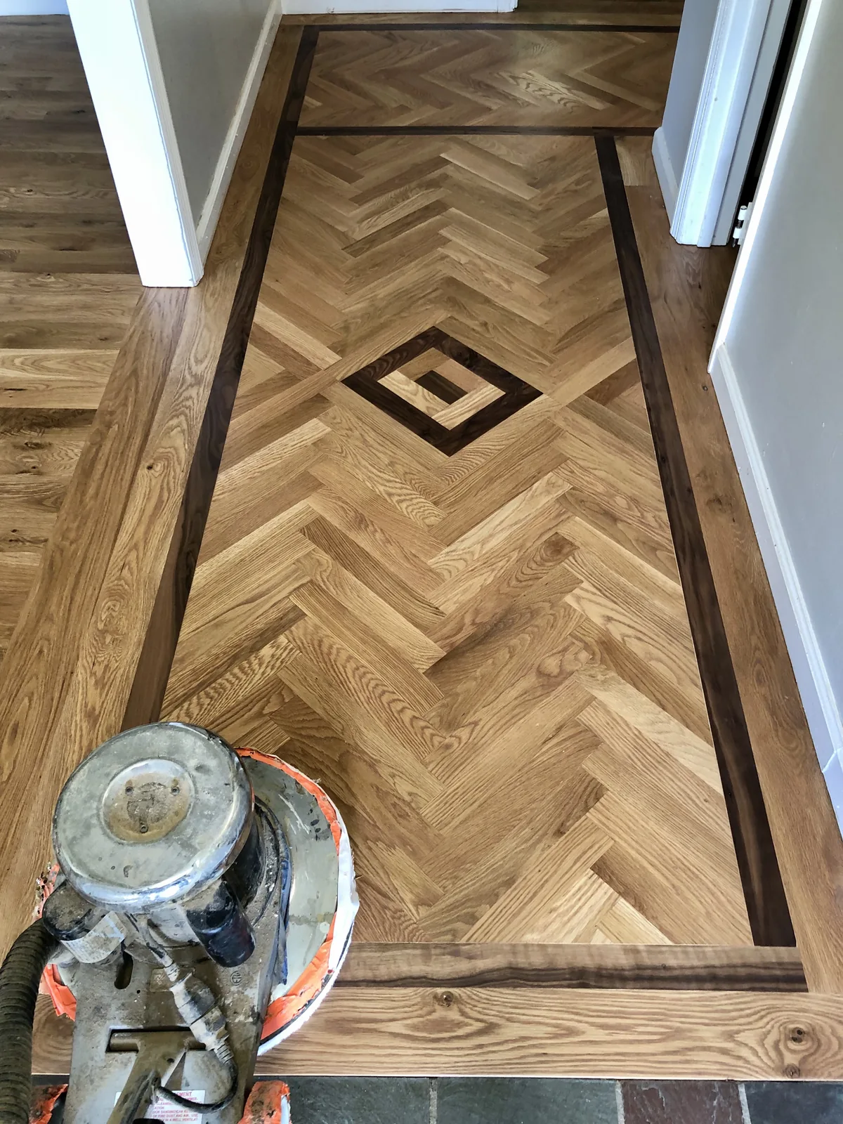 Herringbone oak floor with a dark-framed diamond medallion inlay