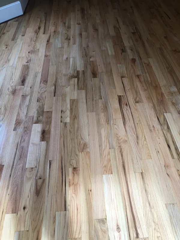 Freshly sanded red oak strip flooring running toward a bright wall