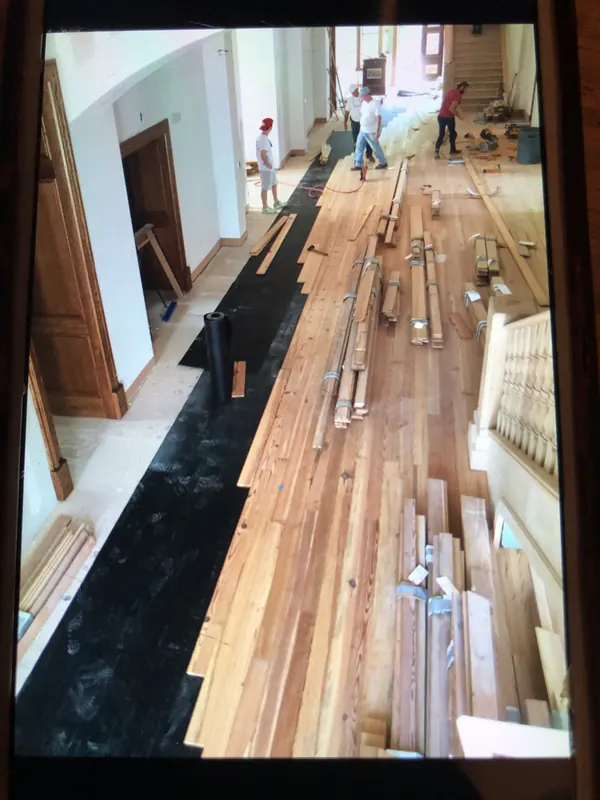 Hallway mid-installation with black underlayment and stacked planks