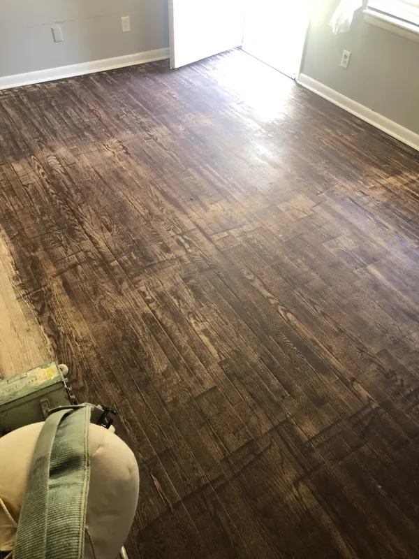 Richly stained dark floor with a tool bag resting in the corner