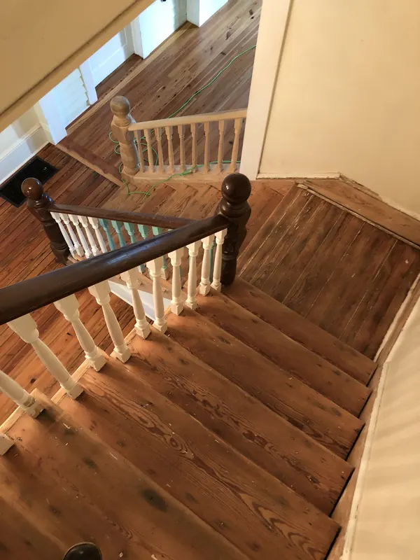 Wooden staircase with turned balusters above a warm landing floor
