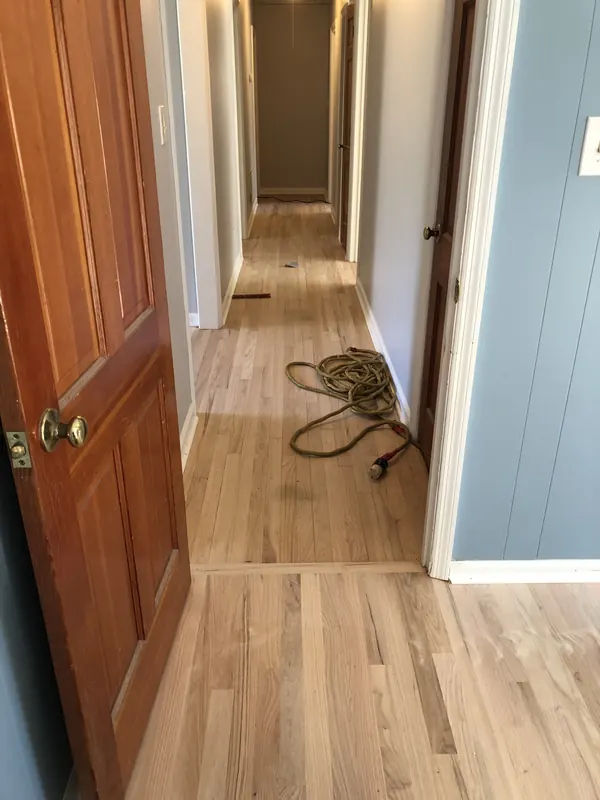 Hallway with pale oak floor and a rope coiled by the doorway