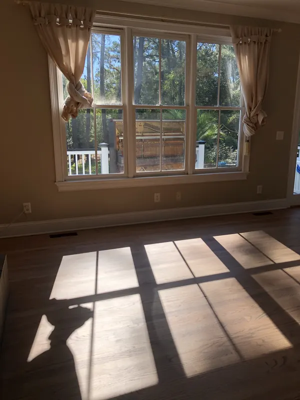 Room with curtained windows and sun stripes across the floor