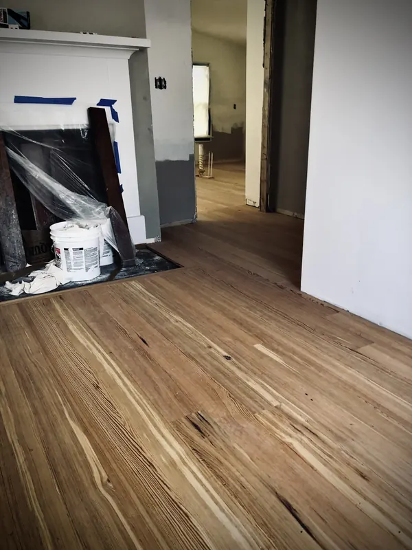 Empty room with light oak floor and a covered bucket