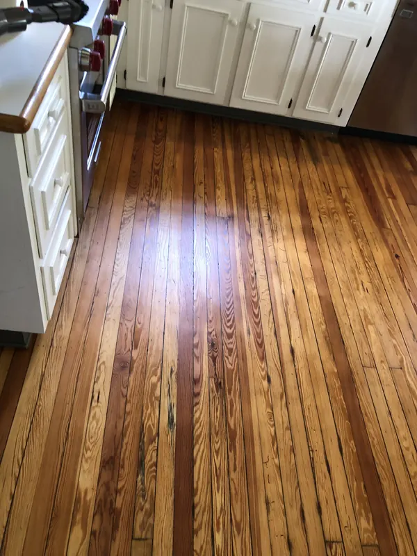 Glossy heart pine floor beside white kitchen cabinets