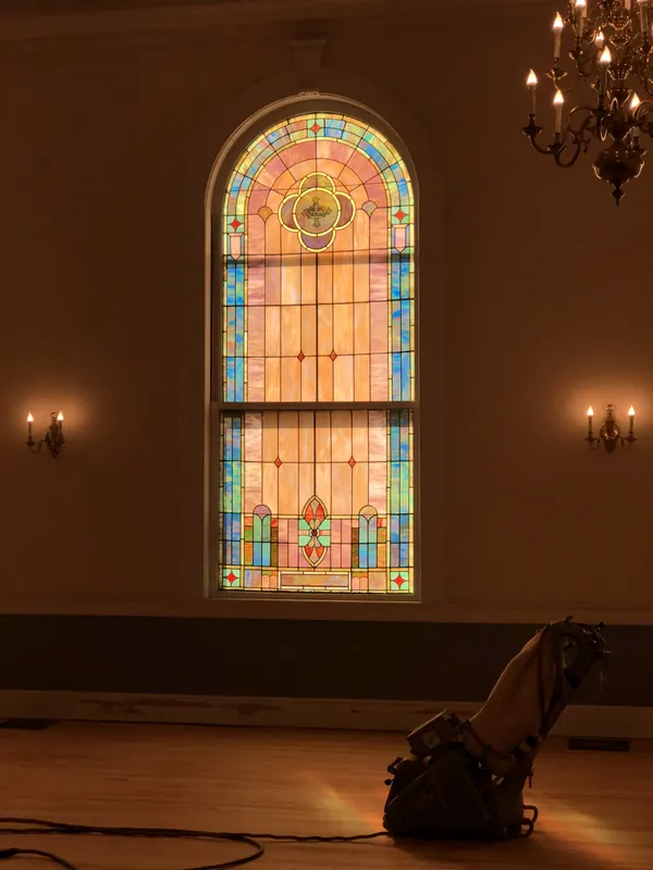 Stained-glass window above a church floor being refinished