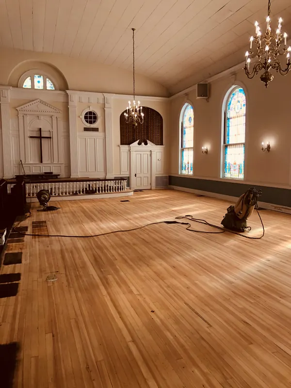Church sanctuary with a warm refinished wood floor and arched windows
