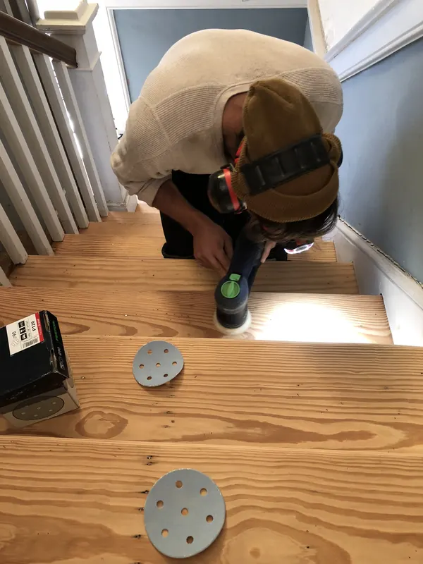 Craftsman kneeling to fit a round vent into a new pine floor
