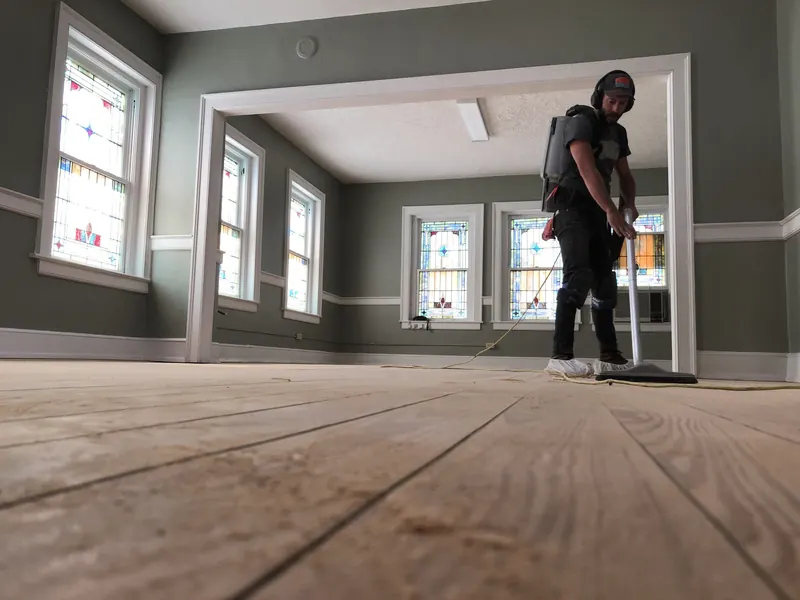 Craftsman running a sander in a bright room with stained-glass windows