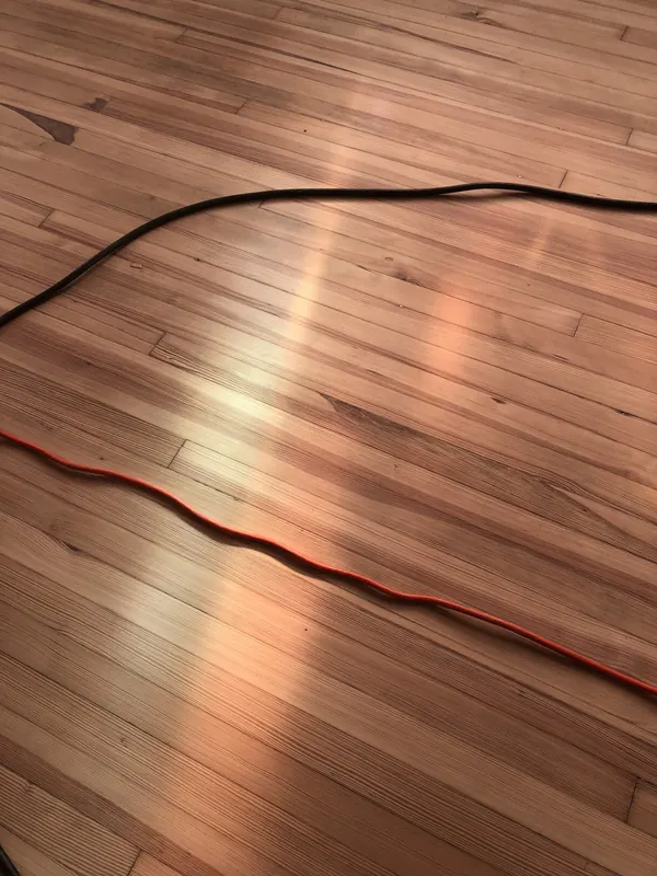Red extension lead curving over a glowing timber floor