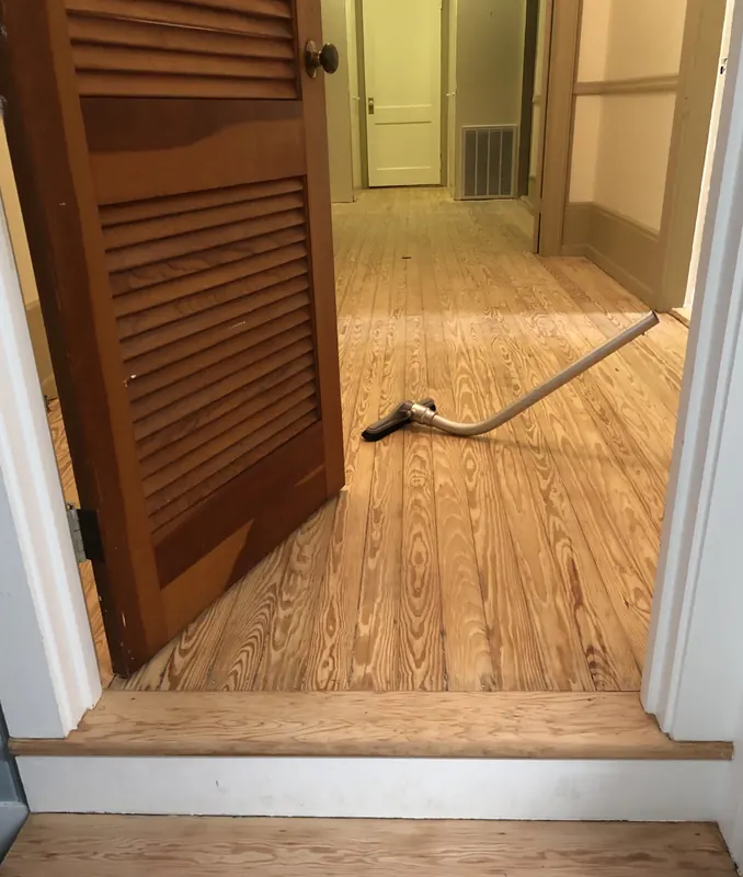 Oak floor meeting a doorway with a wooden louvred door ajar