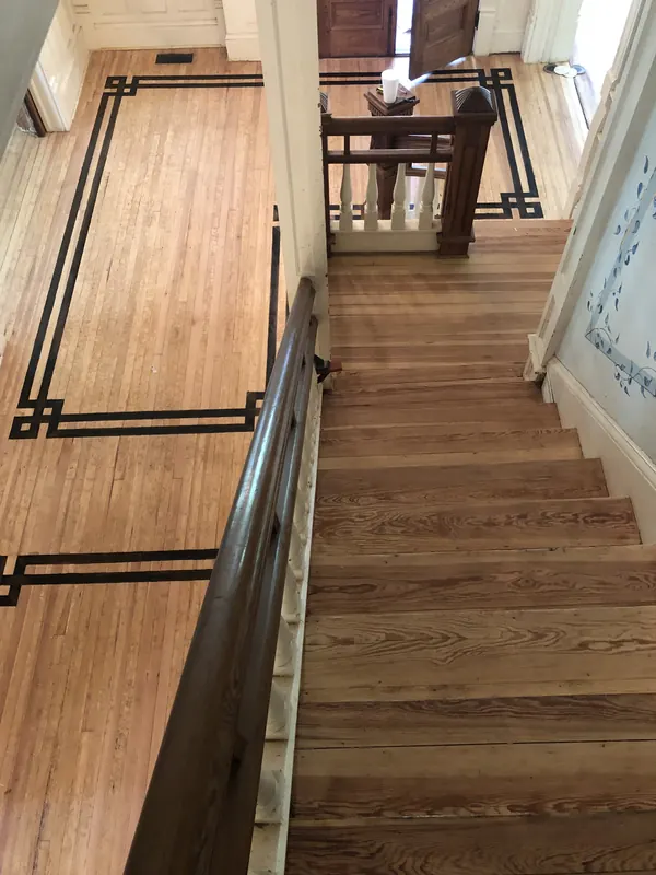 Dark inlaid border strip running along a landing beside a railing