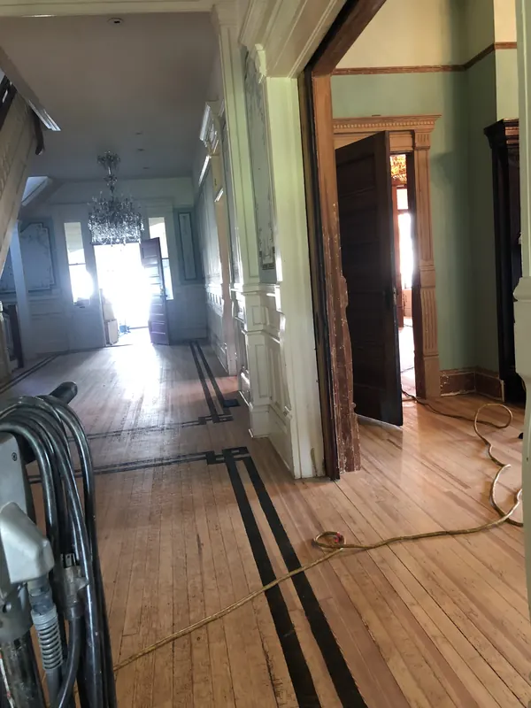 Historic hallway with dark inlay border framing warm pine boards