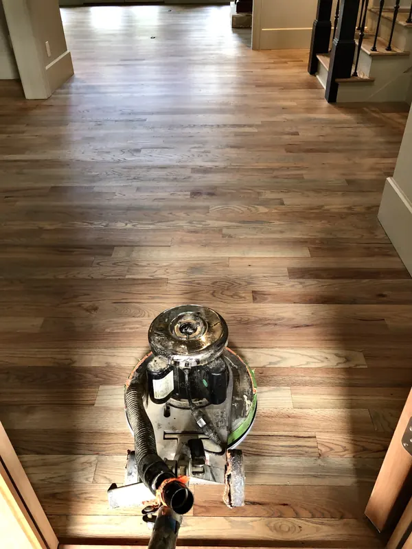 Floor buffer on warm pine boards in a narrow hallway