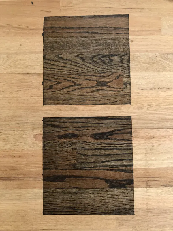 Board with two dark stain samples brushed onto bare oak