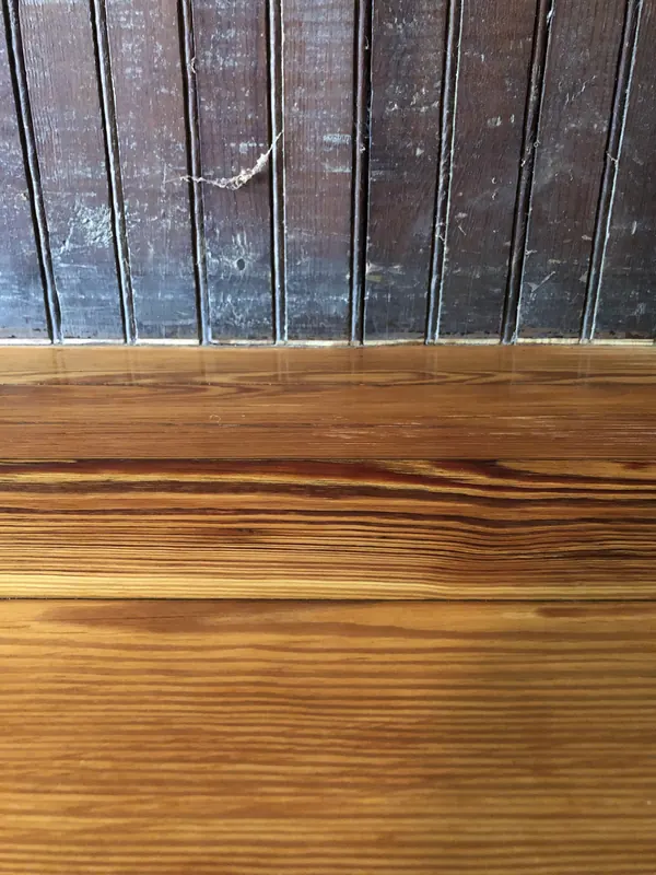 Warm honey pine boards seen beneath a dark stair railing