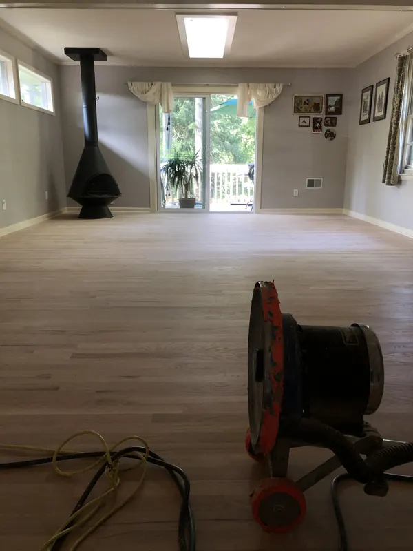 Open room with pale oak floor and a black wood-burning stove