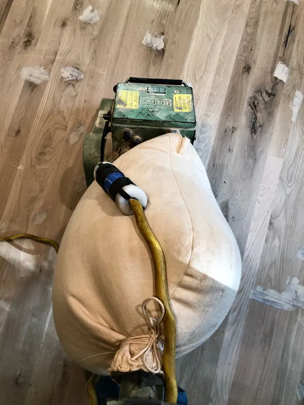 Drum sander with bulging dust bag on part-sanded oak