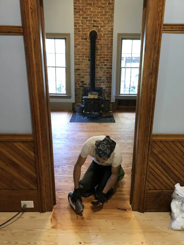 Craftsman working beside a cast iron stove and brick chimney