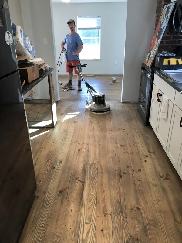 Craftsman running a buffer across a kitchen floor