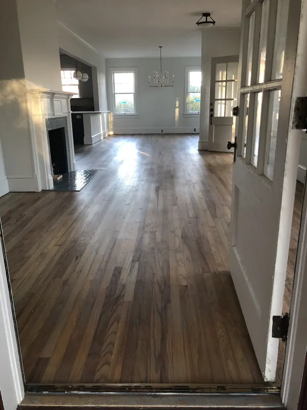 Long view down a dark stained oak floor toward bright windows