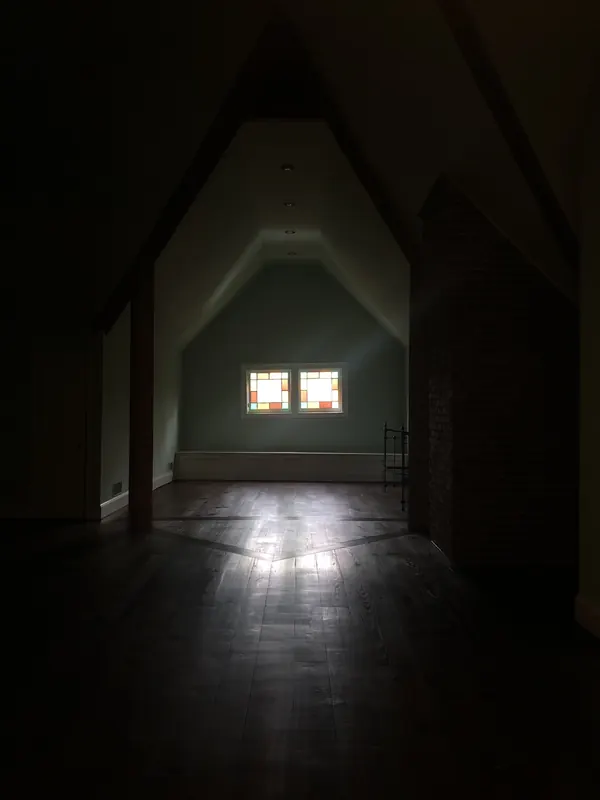 Dark narrow attic hallway with light at the far end