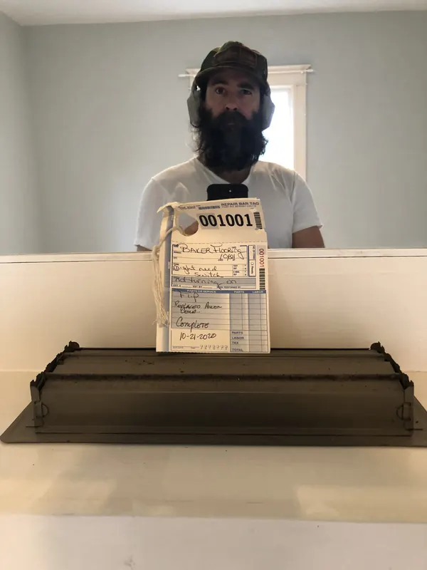 Man holding a finished wooden tray indoors