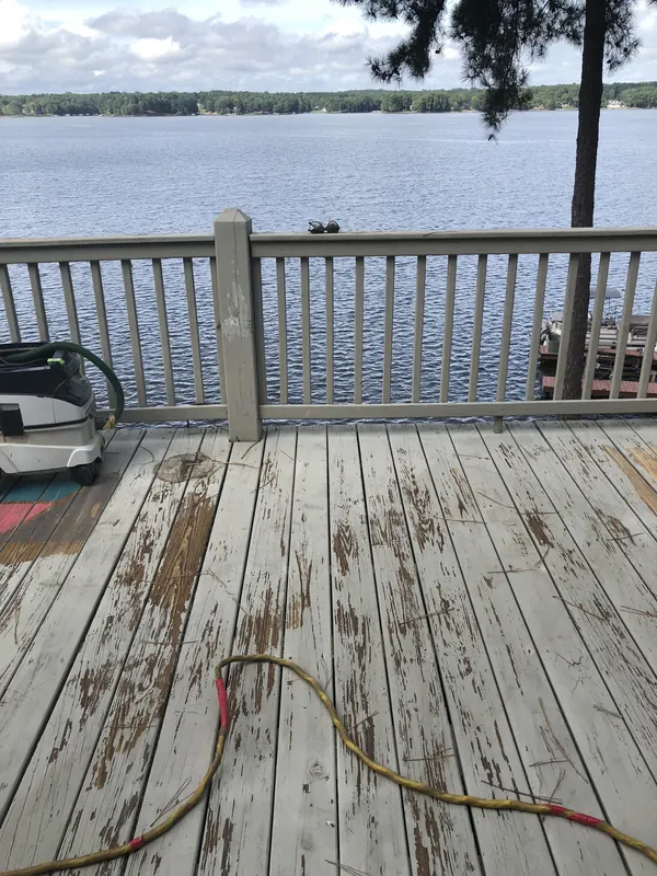 Weathered deck boards beside a lake with a hose across them