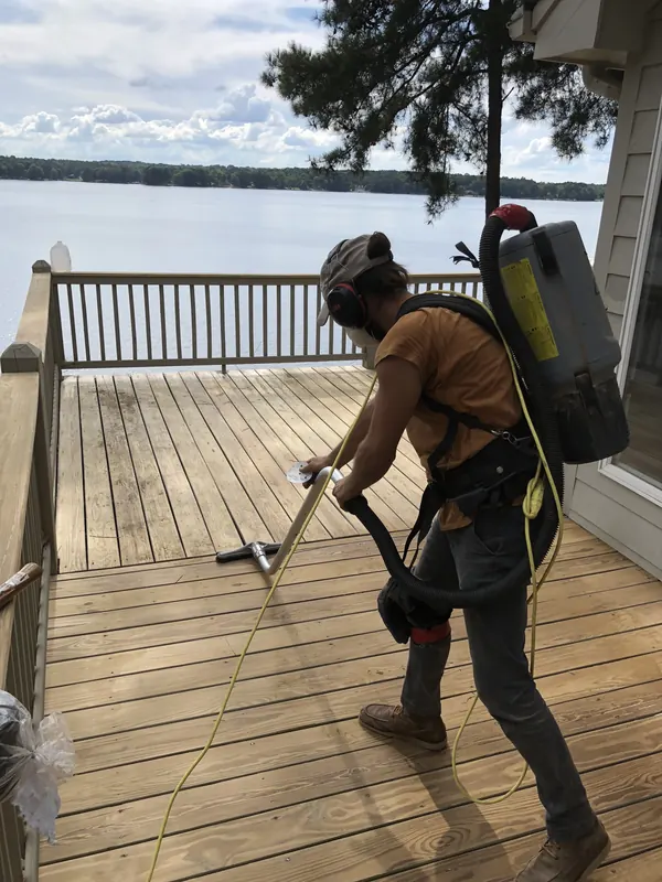 Craftsman pressure-washing a deck overlooking a lake