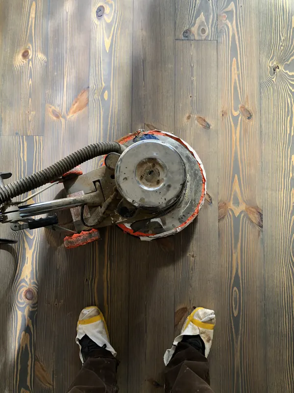 Floor edger and work boots on a grey-toned floor