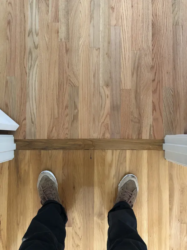 Boots on freshly laid pale flooring at a threshold