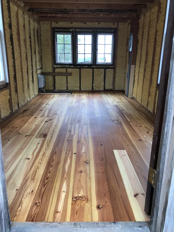 Timber-framed cabin interior with a new heart pine floor