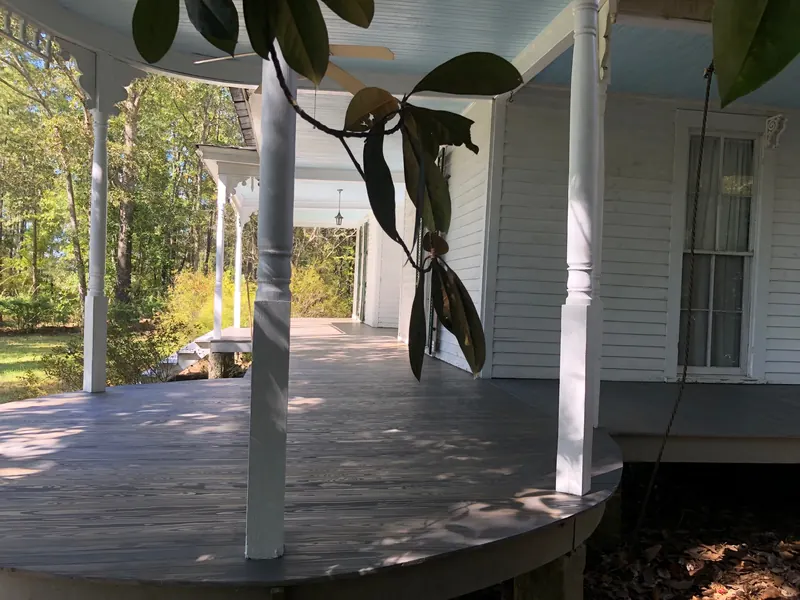 White farmhouse porch with new decking and a magnolia branch