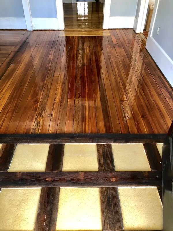 Glossy dark heart pine floor and sunlit steps beyond
