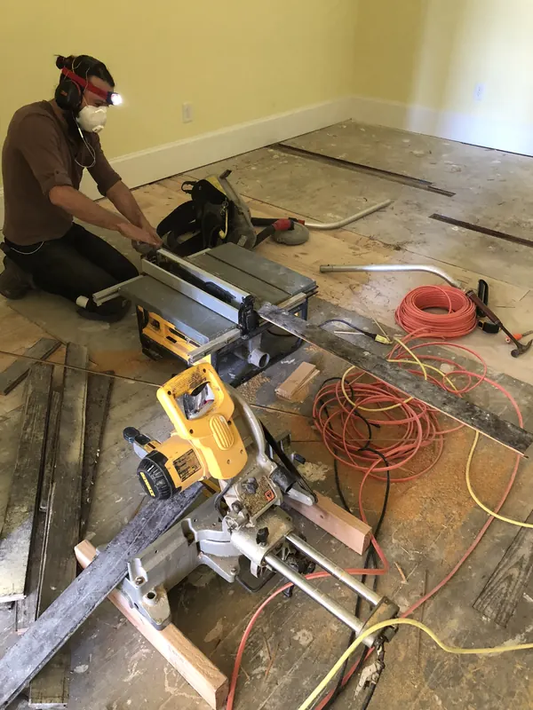 Chop saw set up over an old subfloor with power leads
