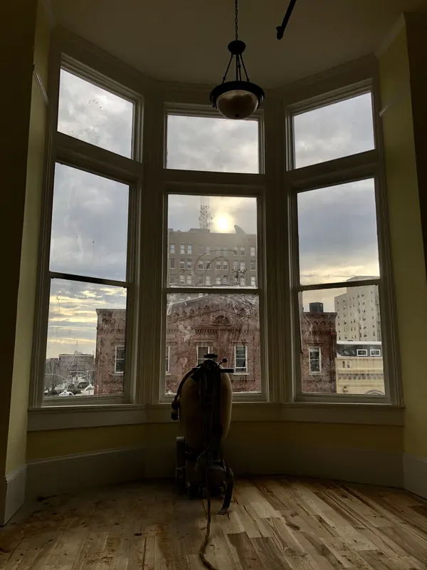 Curved bay window with pale floorboards and a city view