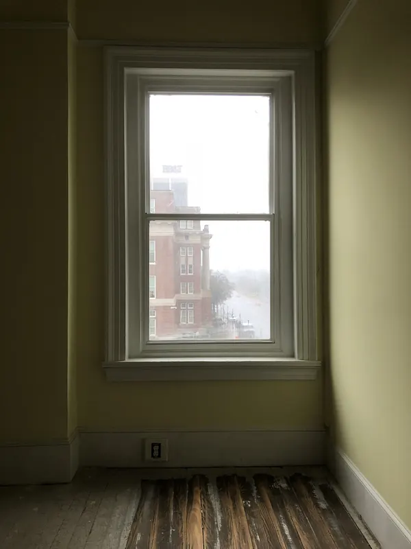 Empty room with a window and dark stained boards