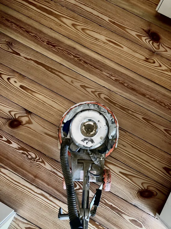 Sander aligned along heart pine boards