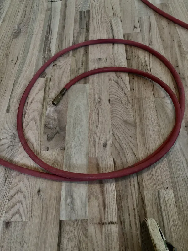 Red air hose coiled on pale new flooring