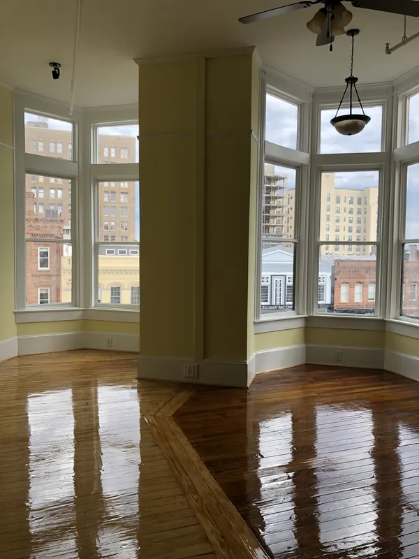 Glossy honey floor reflecting tall bay windows