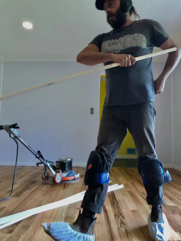 Craftsman drawing a finish applicator across a pale floor