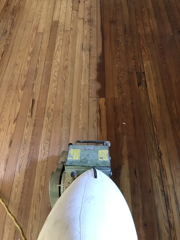 Sander with dust bag on a dark stained floor