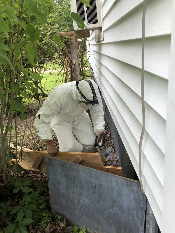 Worker in coveralls beside a trailer outdoors