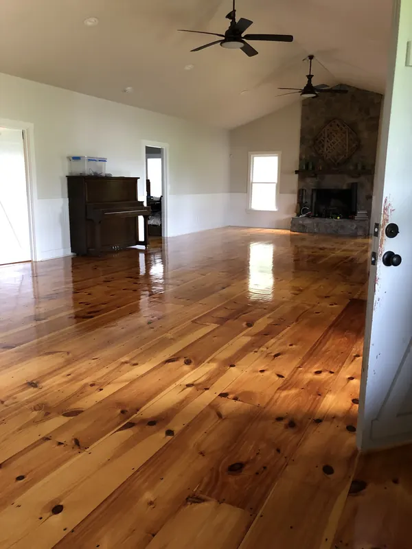 Warm knotty heart pine floor in a vaulted room with a stone fireplace