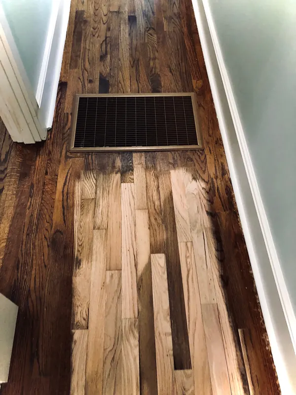 Dark floor with lighter replacement boards let in near a vent