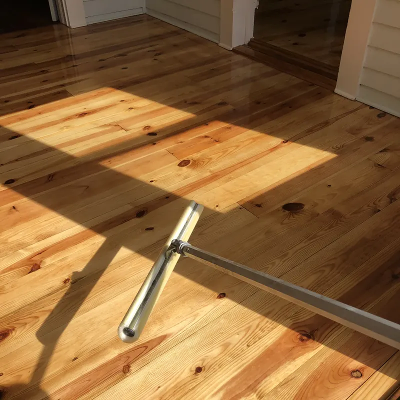 Sunlit pine floor beside a steel handrail