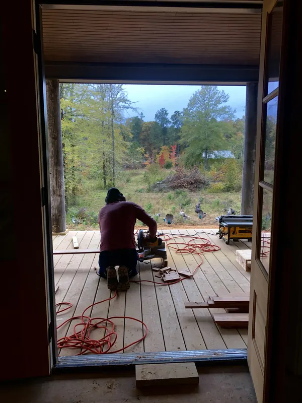New deck boards being laid in a wide doorway onto woodland