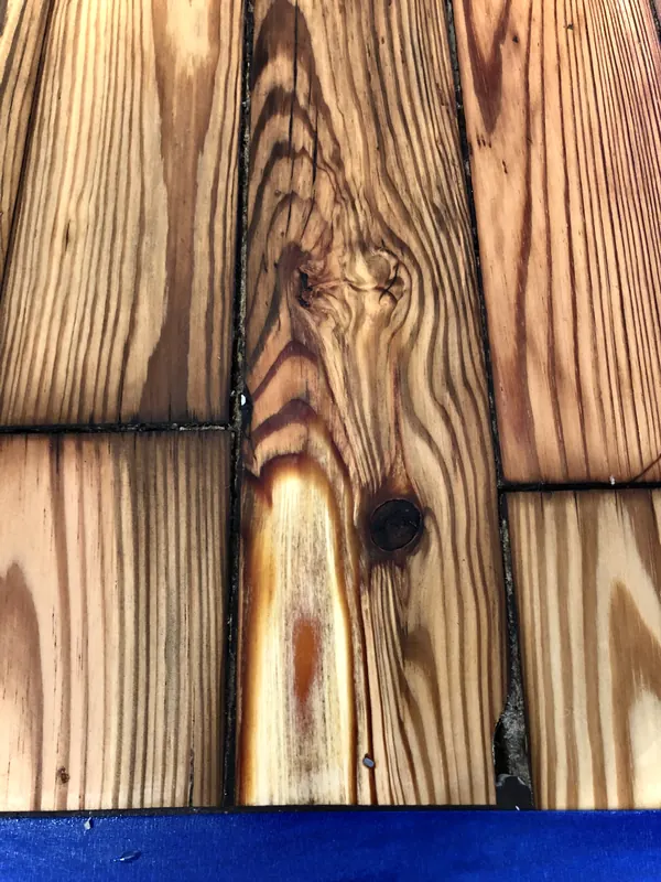 Close view of a pine board with a dark knot and flowing grain