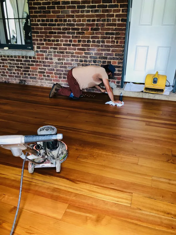 Craftsman kneeling with an edger on a warm floor by a brick wall