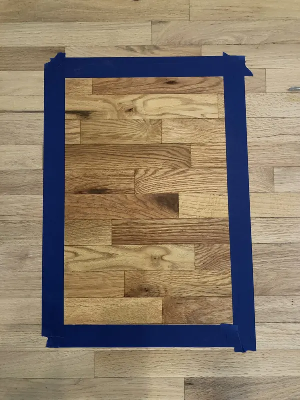 Blue tape marking a rectangle on a pale floor